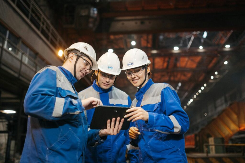 Engenheiros em ambiente industrial discutindo processo comercial com tablet