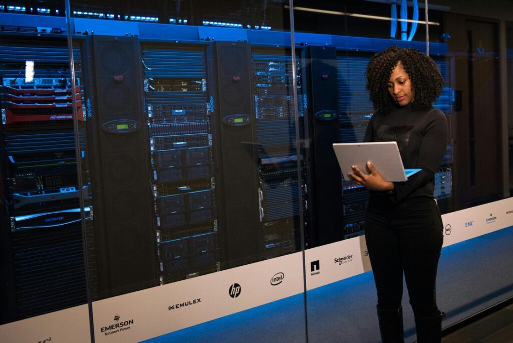 Profissional de TI com laptop monitorando servidores enterprise em data center corporativo
