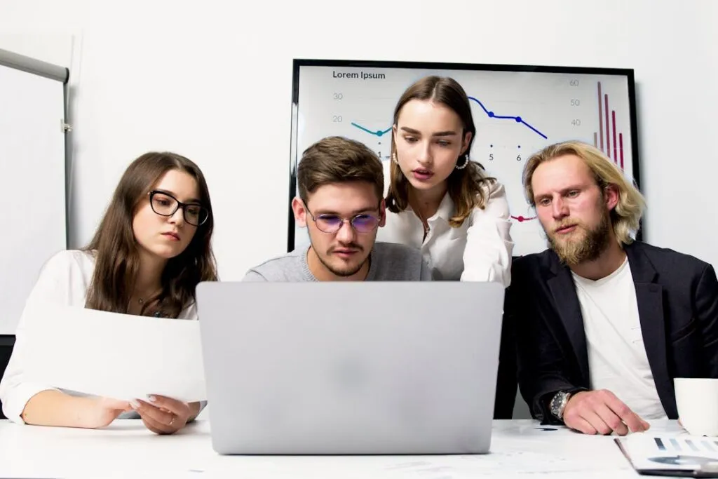 Equipe comercial analisando CRM em laptop com graficos de vendas
