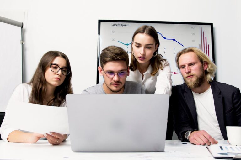Equipe comercial analisando CRM em laptop com graficos de vendas