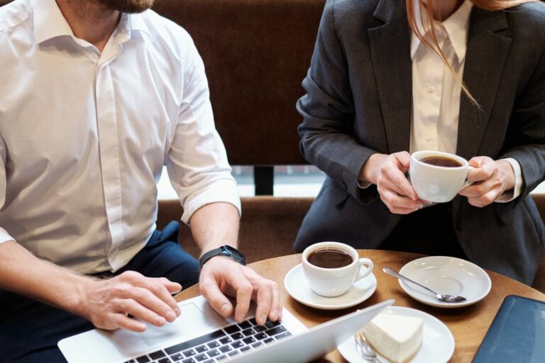 Reunião comercial em ambiente informal com laptop e café