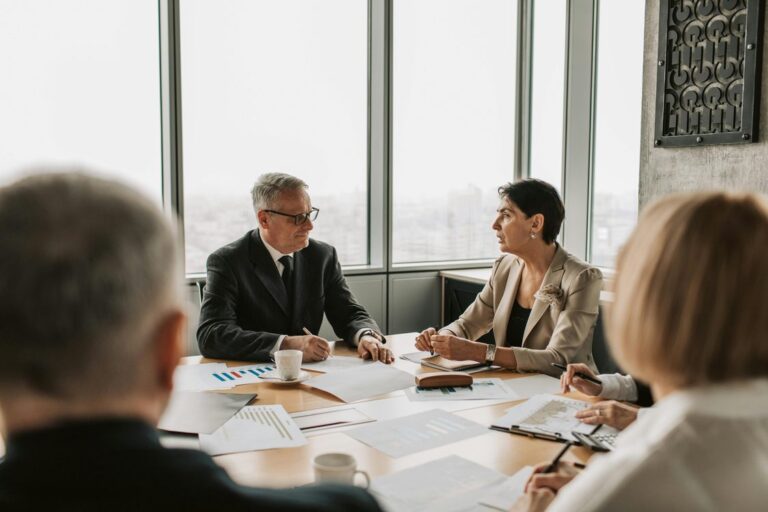 Executivos em reuniao estrategica discutindo documentos na sala de reuniao