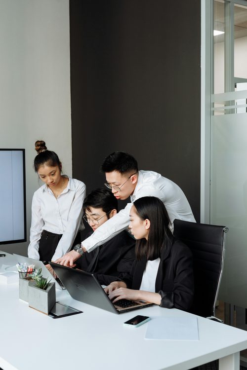 Equipe de profissionais analisando dados em laptop no escritorio