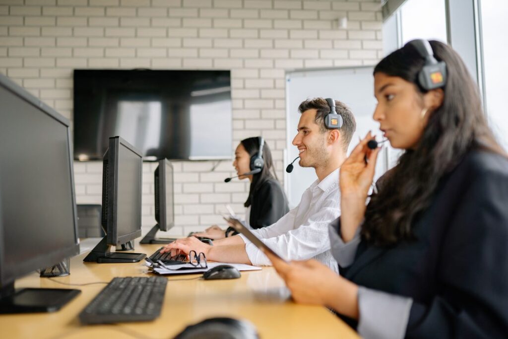 Equipe de pré-vendas com headsets trabalhando em computadores em escritório moderno, representando SDRs em operação de qualificação