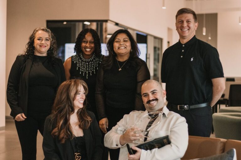 Equipe diversa de seis profissionais celebra premiação corporativa em espaço de escritório moderno