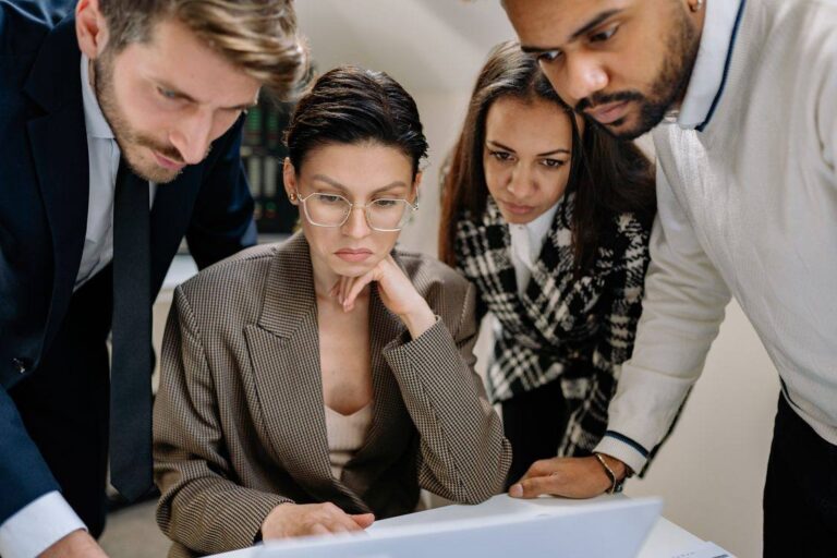 Equipe de customer success analisando dados juntos ao redor de um notebook no escritório