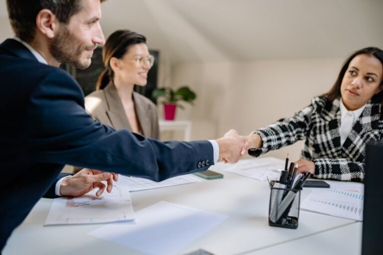 Executivo e cliente realizando aperto de mão após apresentação de proposta comercial com documentos visíveis sobre a mesa em reunião de negócios