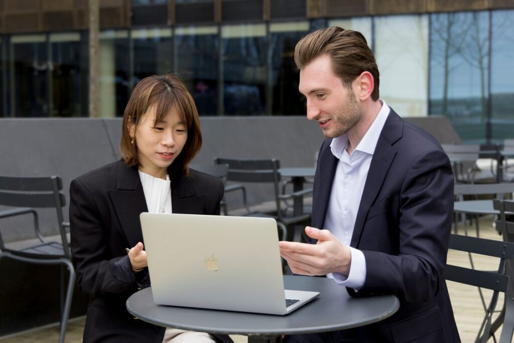 Dois profissionais de negócios analisando oportunidades de prospecção B2B juntos no laptop em ambiente de trabalho moderno