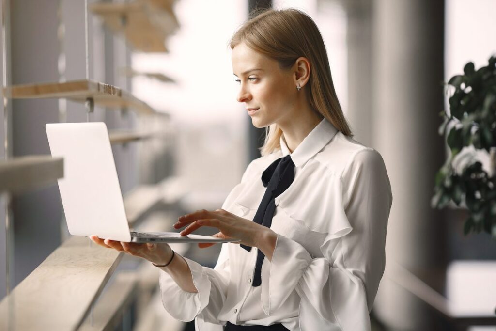 Profissional de vendas B2B concentrada pesquisando e qualificando prospects no laptop em escritório com luz natural