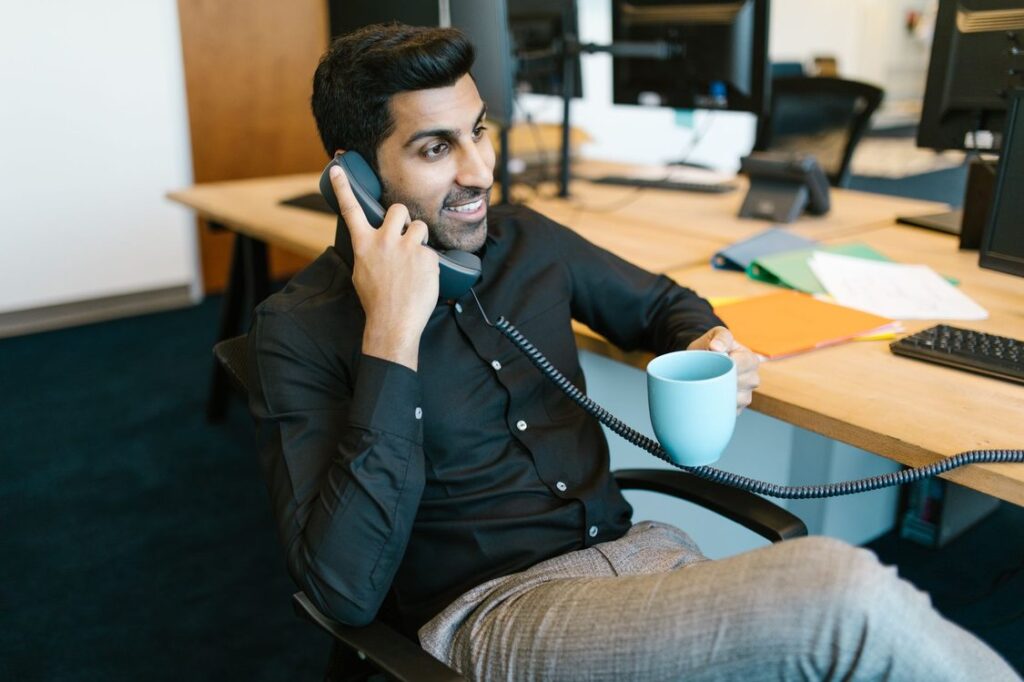 Vendedor sorridente ao telefone em sua mesa no escritório