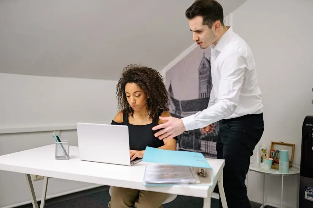 Gestor comercial orientando uma vendedora que trabalha no laptop