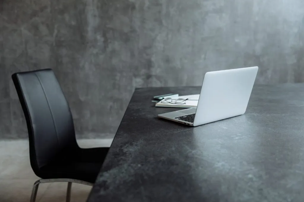 Mesa de escritório vazia com laptop aberto e cadeira desocupada