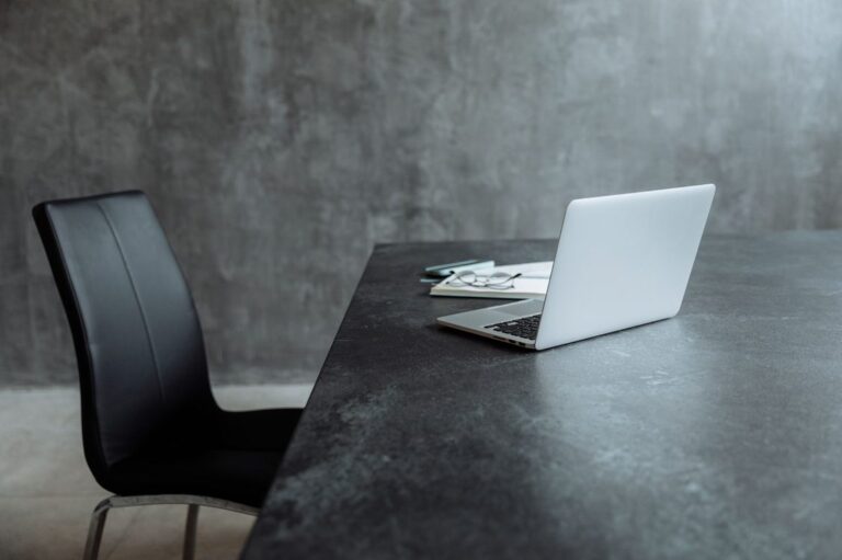 Mesa de escritório vazia com laptop aberto e cadeira desocupada