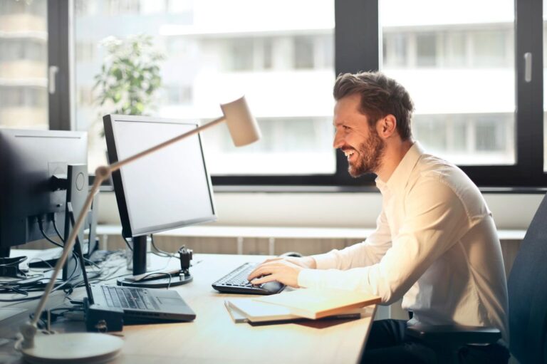 Profissional sorrindo enquanto escreve no computador do escritório