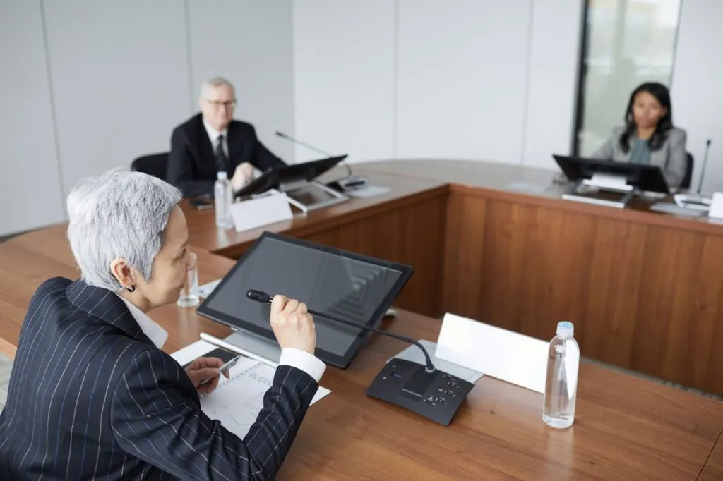 Executiva falando em reunião de diretoria com orçamento sobre a mesa