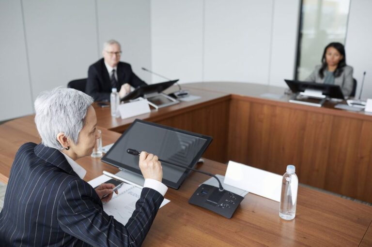 Executiva falando em reunião de diretoria com orçamento sobre a mesa