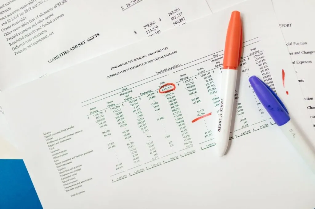 Planilha financeira com números destacados e canetas marca-texto